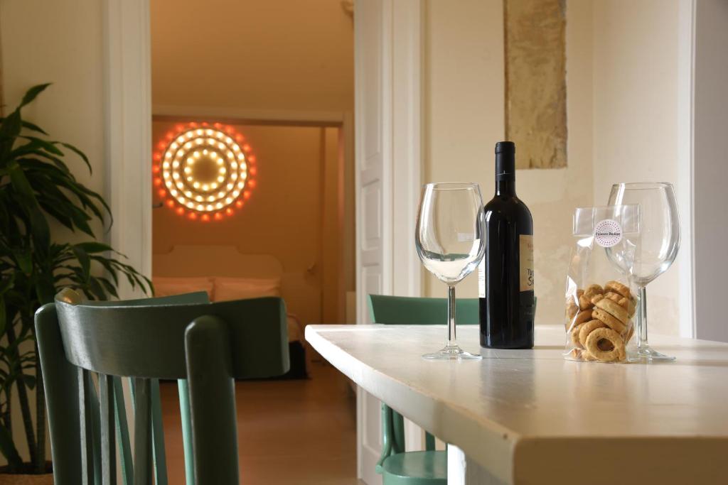 - une bouteille de vin assise sur une table avec 2 verres à vin dans l'établissement Palazzo Rudiae - Sant'Irene, à Lecce