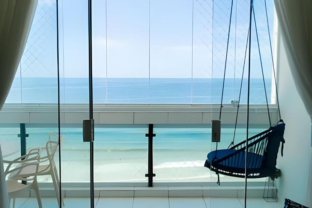 a view of the beach from a room with a swing at Desperte com o Azul do Mar na Sua Janela! in Guarujá