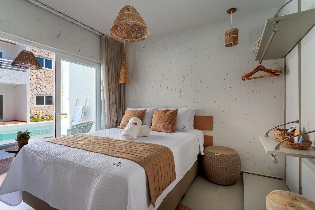 ein Schlafzimmer mit einem Bett, auf dem ein Stofftier liegt in der Unterkunft Apartamentos Moana Milagres - Rota Ecológica Milagres in Barra do Camaragibe