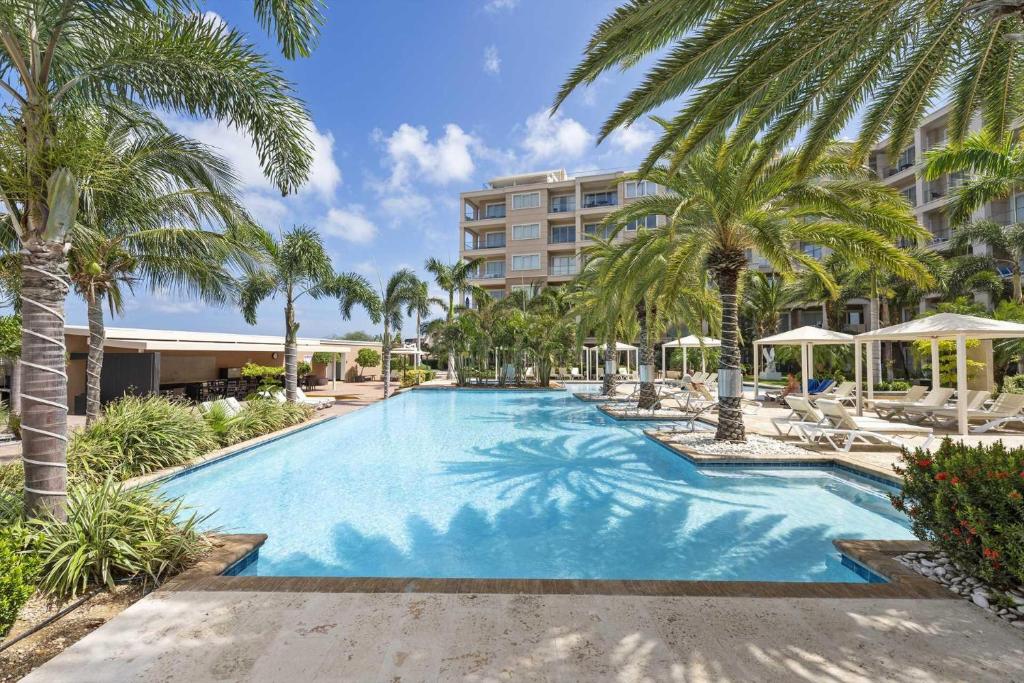 a large swimming pool with palm trees and a building at Eagle Beach - Luxury Beachscape 2BR condo - LV302 in Palm-Eagle Beach
