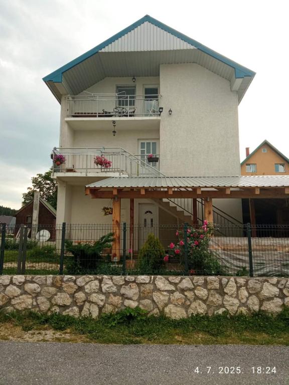 a large white house with a fence in front of it at Apartman Lucija in Žabljak
