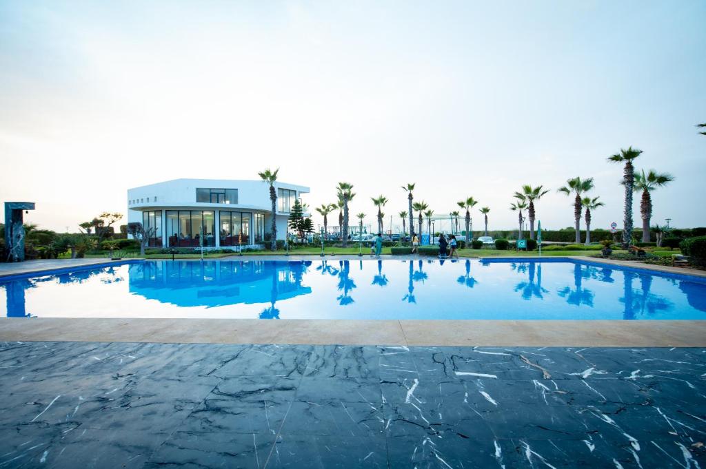 a large swimming pool with palm trees and a building at Garden Bay Appart'Hôtel in Casablanca