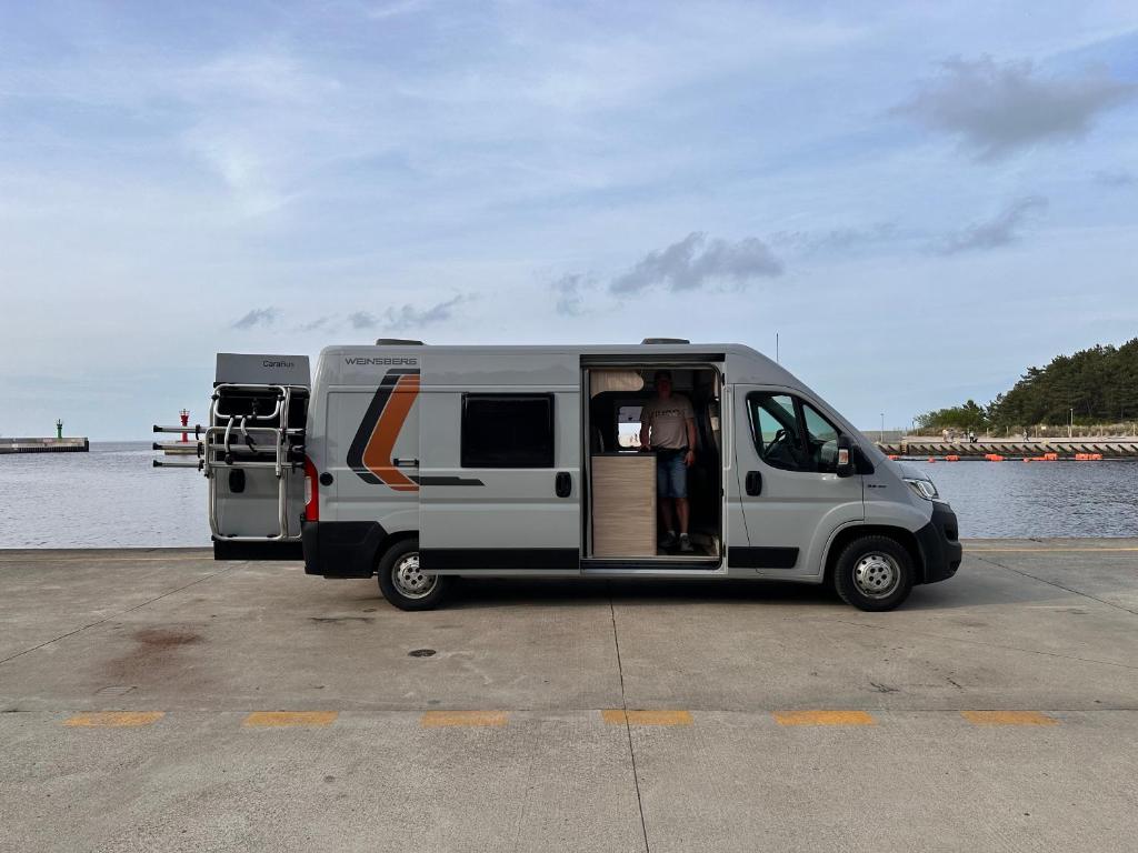 a white camper van parked next to a body of water at Kamper na urlop in Mrzeżyno