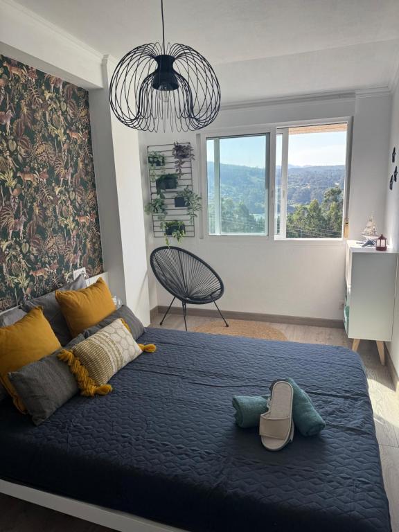 Schlafzimmer mit einem großen blauen Bett und einem Kronleuchter in der Unterkunft Una Parada en el Camino 3 in Fisterra