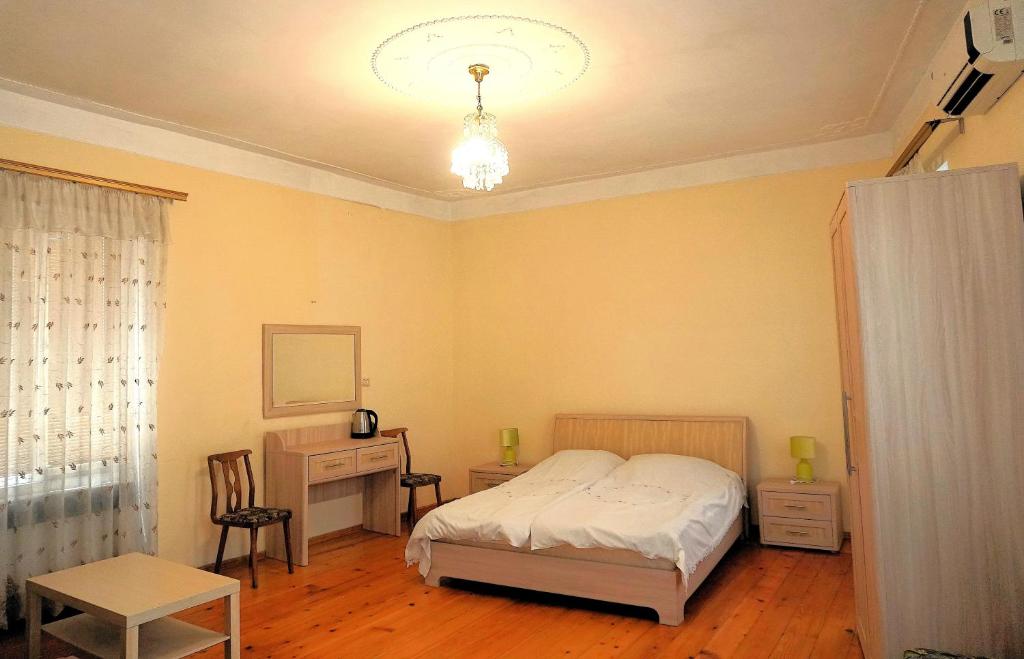 a bedroom with a bed and a desk and a chair at Pospolita Guest House in Kutaisi