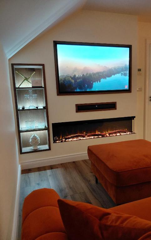 a living room with a flat screen tv above a fireplace at Macaldrack's Loft in Dunloy