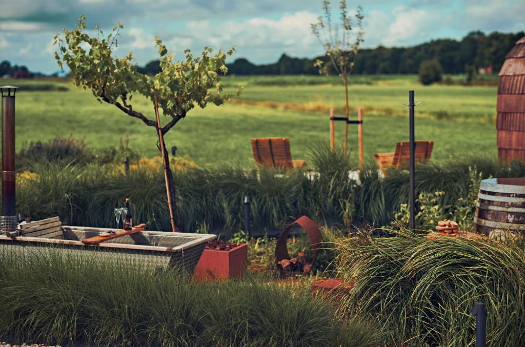 a garden with a tree in the middle of a field at Nest - luxe wellness met privé sauna in Friesland in Luxwoude