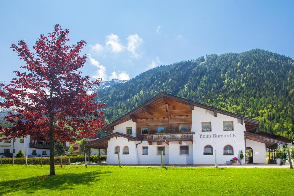ein Gebäude mit einem Baum vor einem Berg in der Unterkunft Romantik Ferienwohnungen in Pertisau