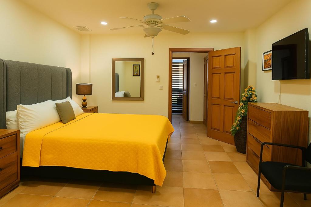 ein Schlafzimmer mit einem gelben Bett und einem TV in der Unterkunft Ave Fénix Cozumel in Cozumel