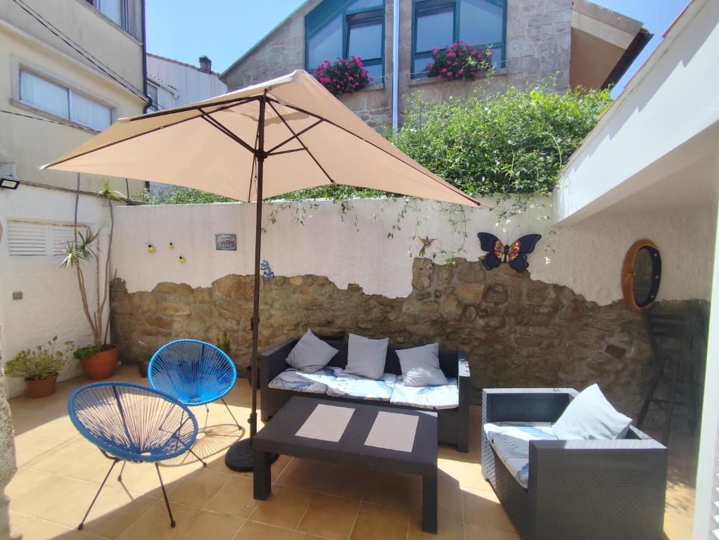 a patio with a table and an umbrella and chairs at Casa O Castriño in Cambados