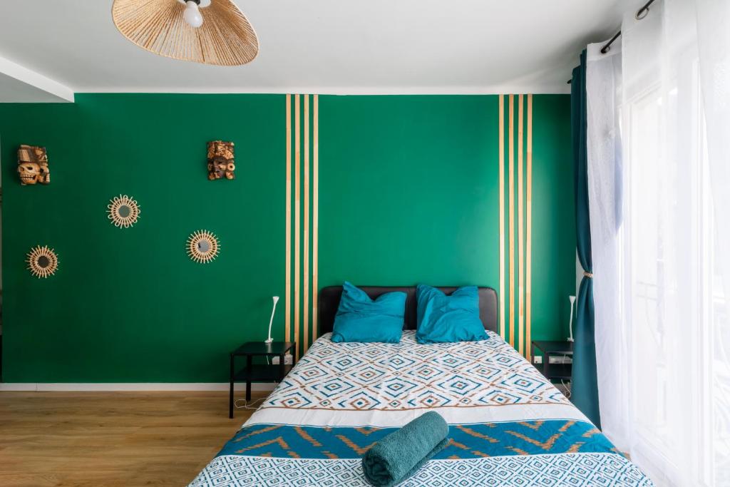 - une chambre avec des murs verts et un lit avec des oreillers bleus dans l'établissement le cocon du peyrou, à Montpellier