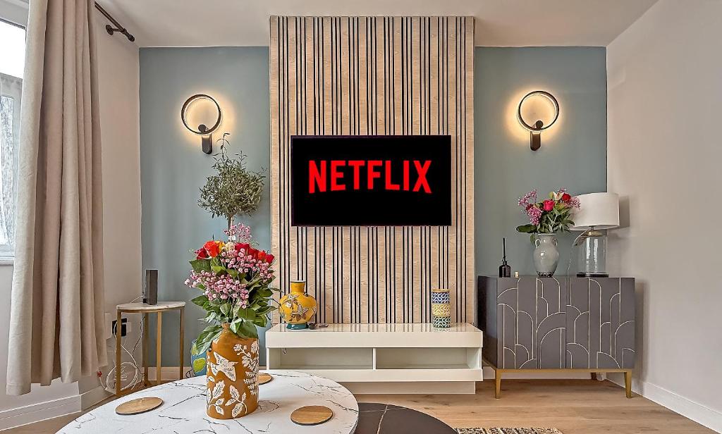 a living room with a netflix sign on the wall at LUTON LUXURY LIVING, Large PREMIUM House, Beautifully Landscaped PRIVATE GARDEN, Newly Refurbished Throughout, PARKING FOR 2 VEHICLES, Great Access to Central Luton & the M1 Motorway in Luton