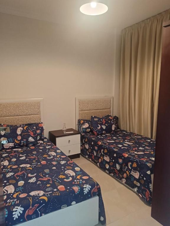 a bedroom with two beds and a dresser and a bedskirts at بورتو الجولف in Dawwār Abū Maḩrūs