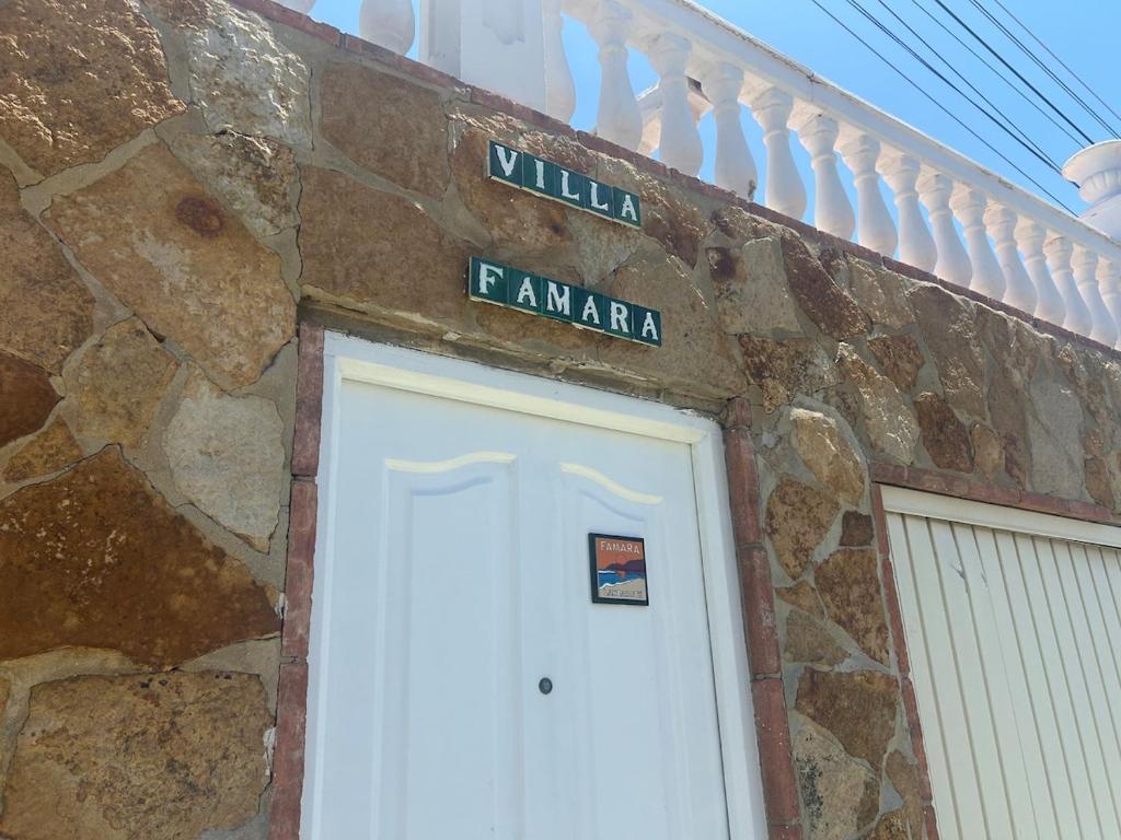 a stone building with a white door and a street sign at CASA RURAL MALAGA,VILLA FAMARA,10 personas,DESAYUNO ANDALUZ INCLUIDO EN EL PRECIO in Málaga
