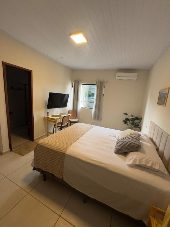 a bedroom with a bed and a table and a desk at Flat 02 - Novo e completo em Bonito, Pernambuco in Bonito