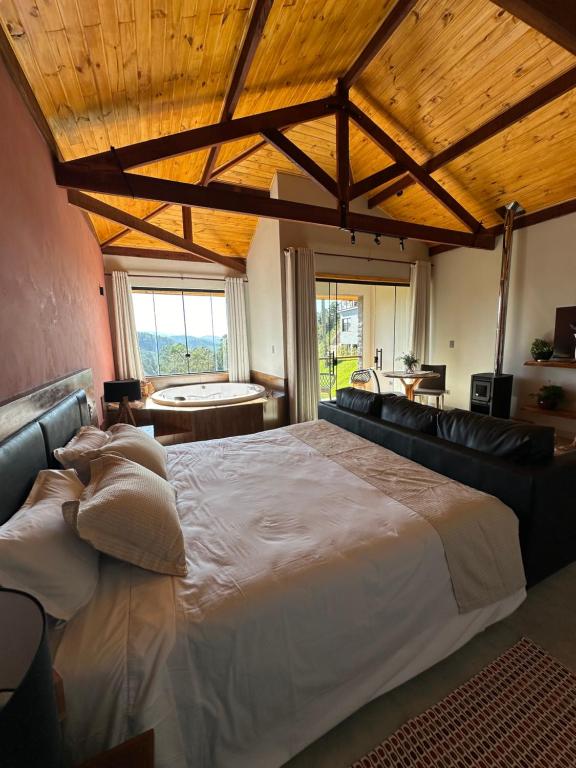 a large bed in a room with a wooden ceiling at Quinta da Serra Villa & Chalés in Santo Antônio do Pinhal