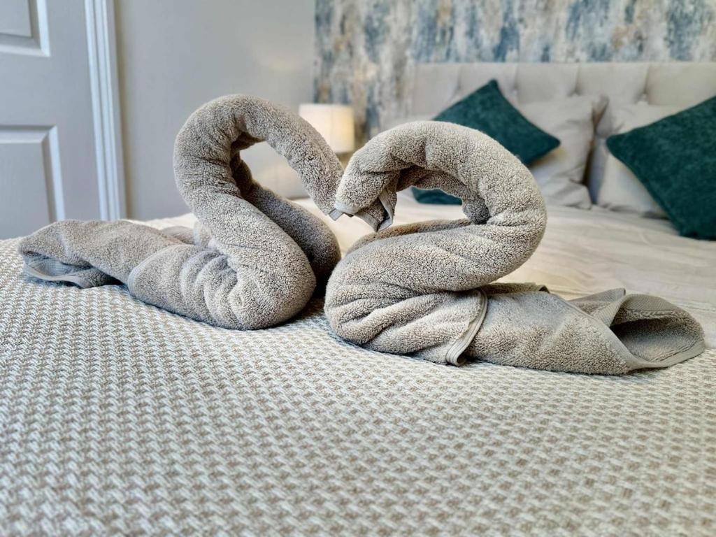 two swans are sitting on top of a bed at Botanica convenient centre Stay free parking in Swindon