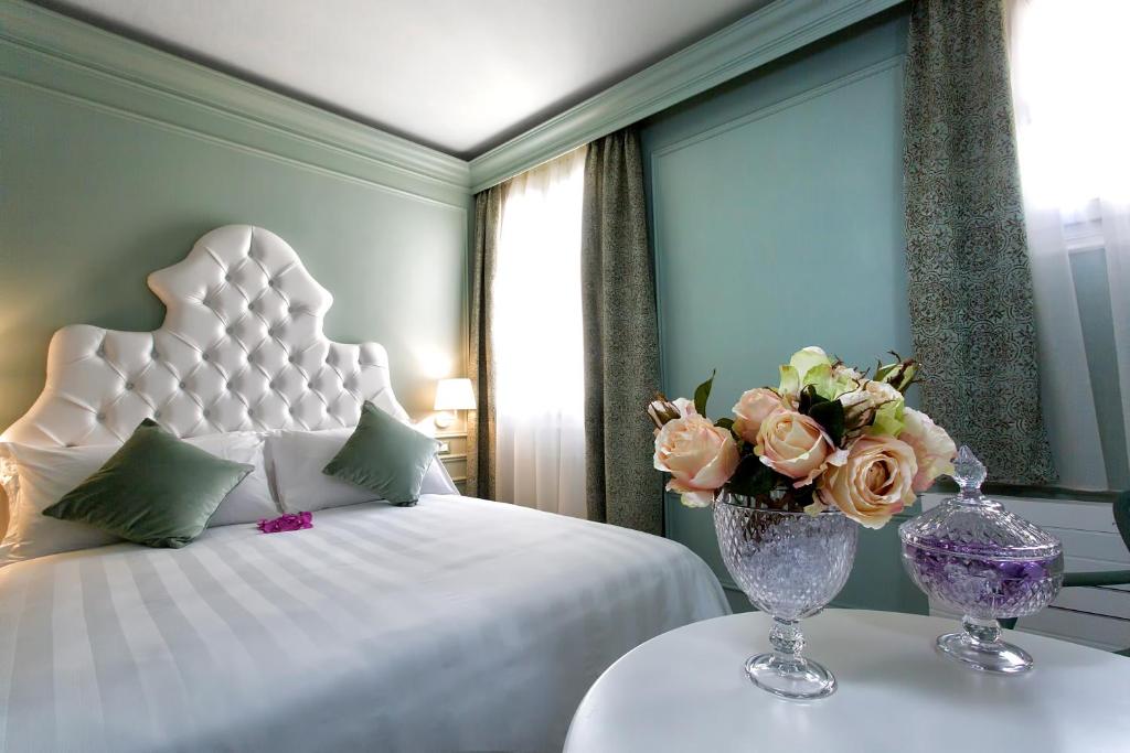 1 dormitorio con 1 cama y un jarrón de flores sobre una mesa en Aquamare, boutique b&b, en Venecia