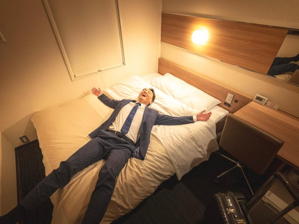 Postel nebo postele na pokoji v ubytování Super Hotel JR Shin-Osaka Higashiguchi