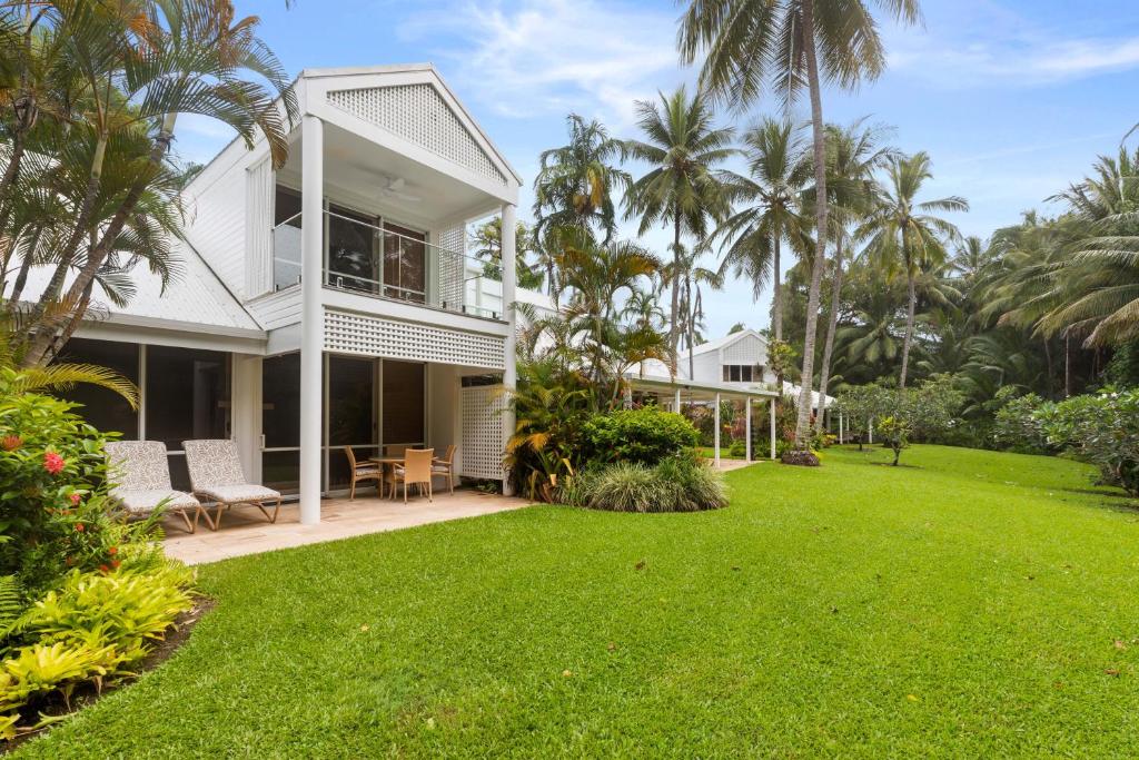 uma casa branca com um quintal com um cachorro na frente em Mirage Resort Villa 105 with access to Sheraton Facilities em Port Douglas