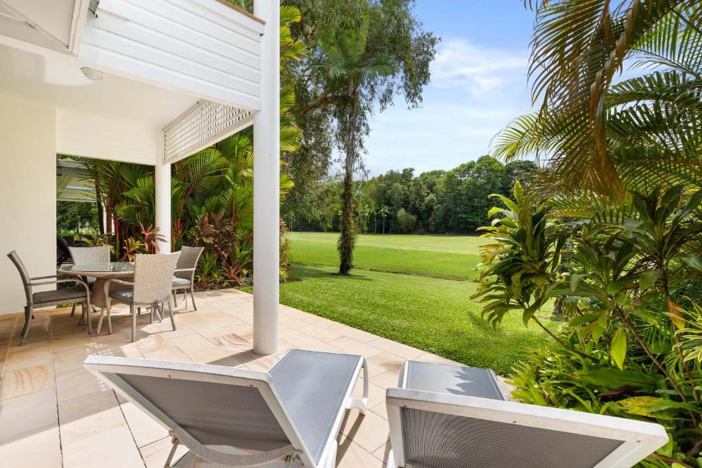 um pátio com cadeiras, uma mesa e um relvado em Mirage Resort Villa 124 with access to Sheraton Facilities em Port Douglas