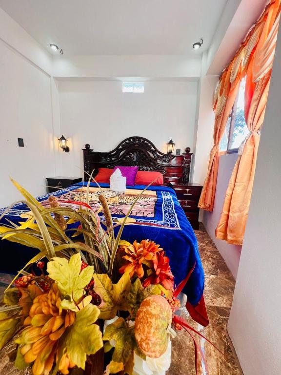 a bedroom with a bed and a table with flowers at Casa Don 20 in San Marcos La Laguna
