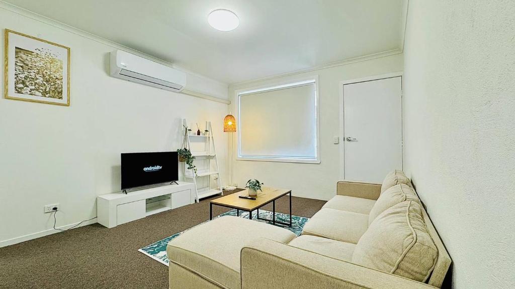 a living room with a couch and a tv at Cozy 2BR Retreat, 3-Minute Drive to Albury Airport in Albury