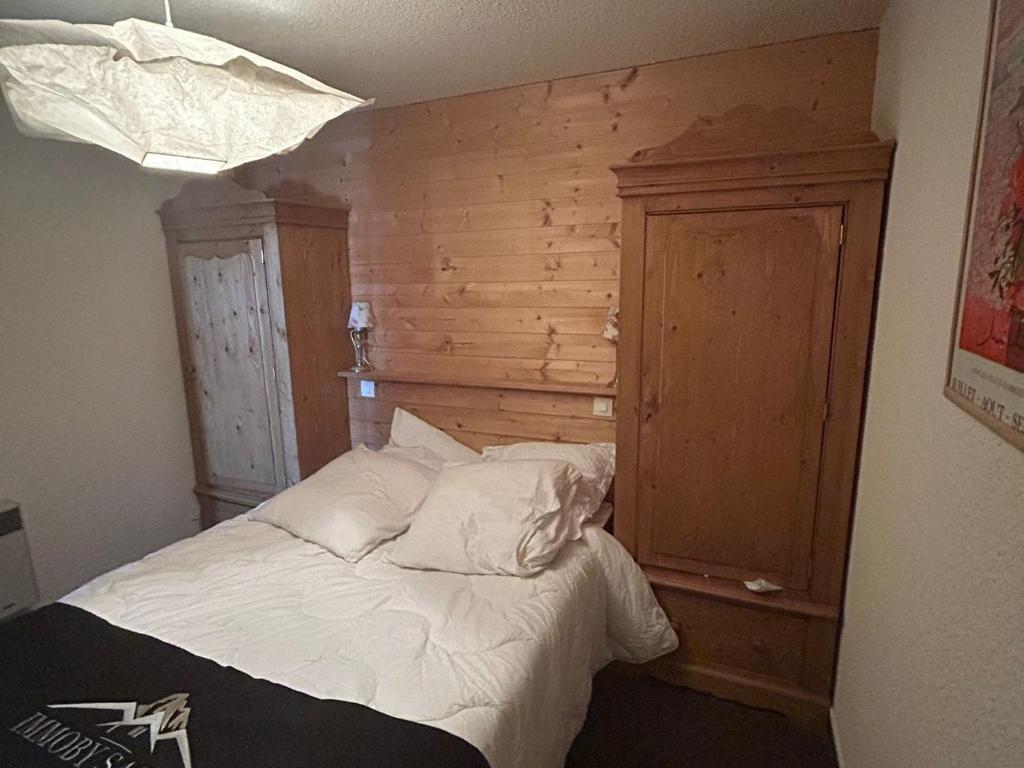 - une chambre avec un lit blanc et un mur en bois dans l'établissement Appartement confort pour 4/6 pers. au cœur de la station avec terrasse - FR-1-814-140, à Besse-et-Saint-Anastaise