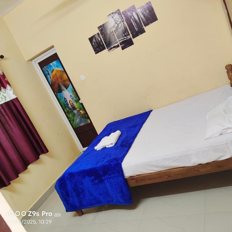 a bedroom with a bed with a blue blanket on it at Anaswaramholidays in Jāmb