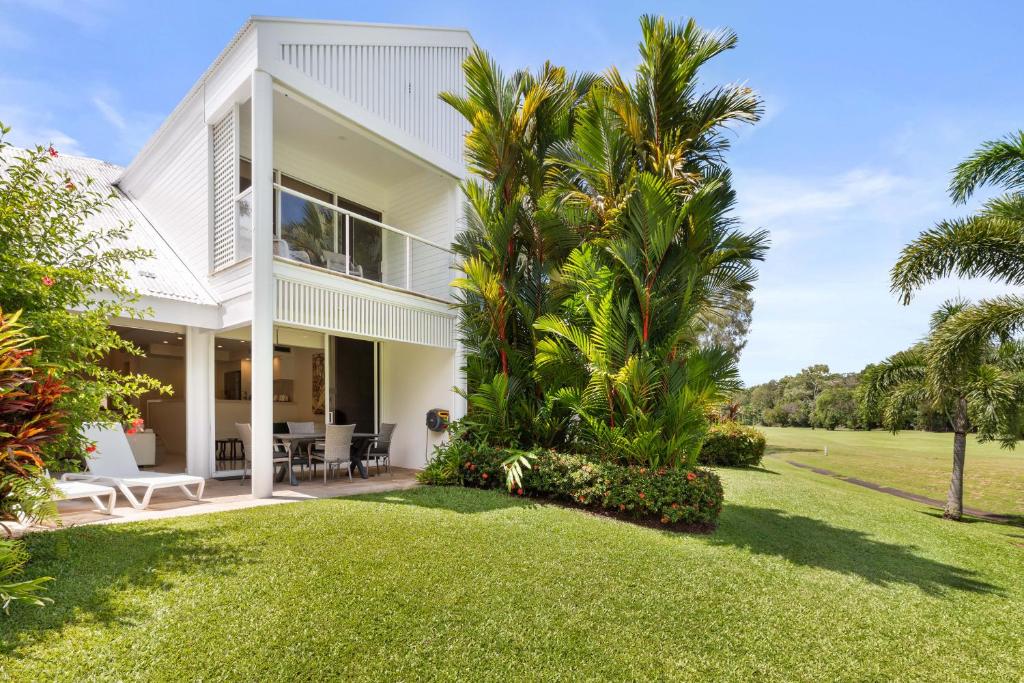 una vista exterior de una casa blanca con palmeras en Mirage Resort Villa 152 with access to Sheraton Facilities, en Port Douglas