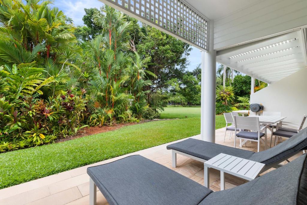 un patio con mesa, sillas y césped en Mirage Resort Villa 173 with access to Sheraton Facilities, en Port Douglas