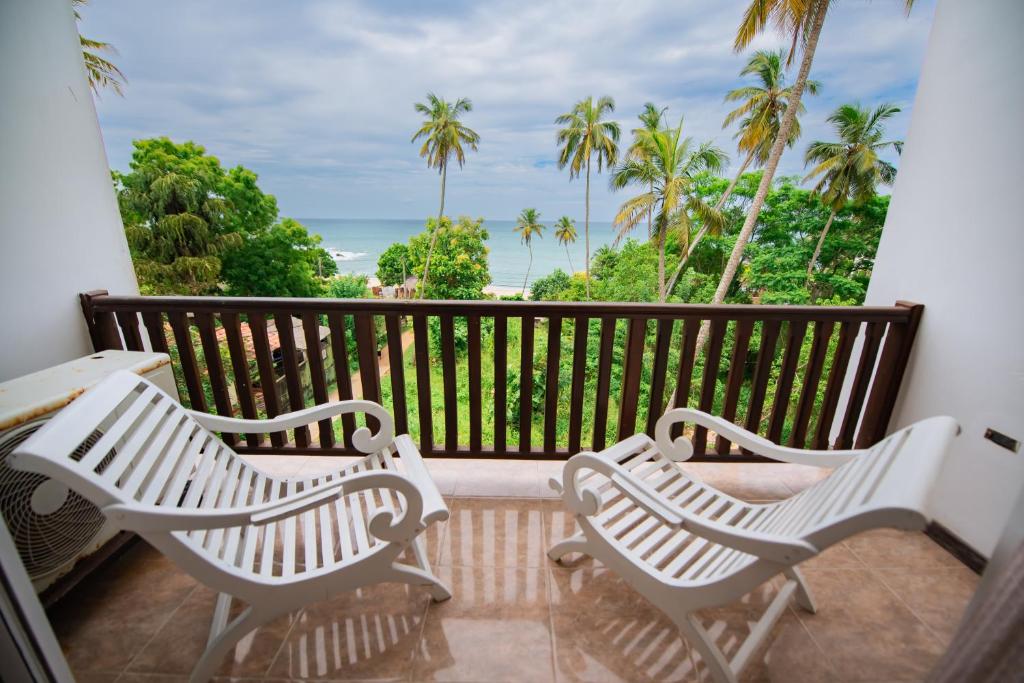 un balcon avec deux bancs blancs et des palmiers dans l'établissement Sole Luna Resort & Spa, à Tangalle