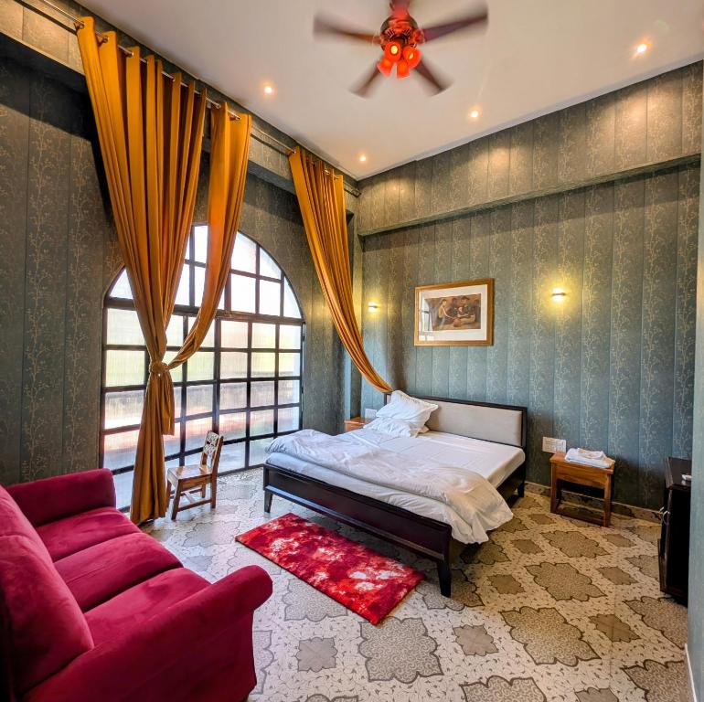 PipalsānaQila Hotel的带一张床和一张红色沙发的卧室