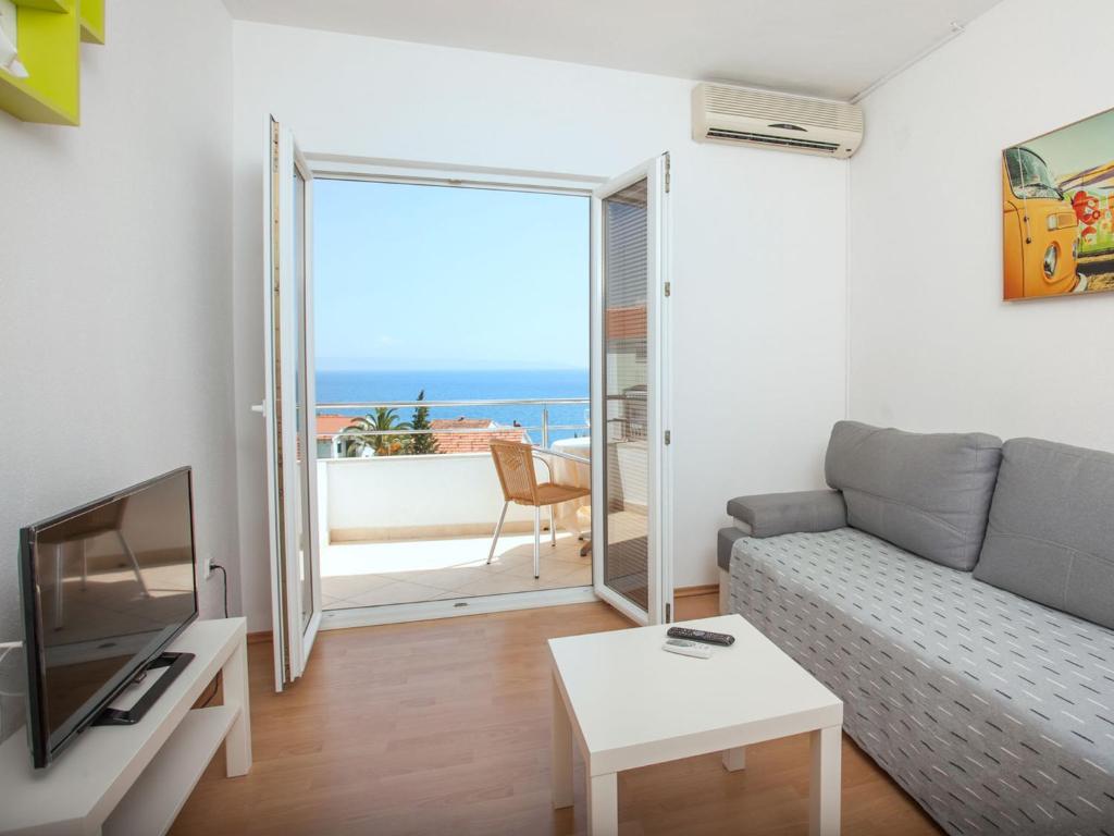 a living room with a couch and a tv and a balcony at Apartments Kairos in Seget Vranjica