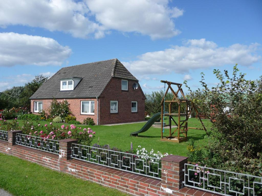 uma casa com um jardim e um parque infantil em Haus Heverstrom em Westerhever