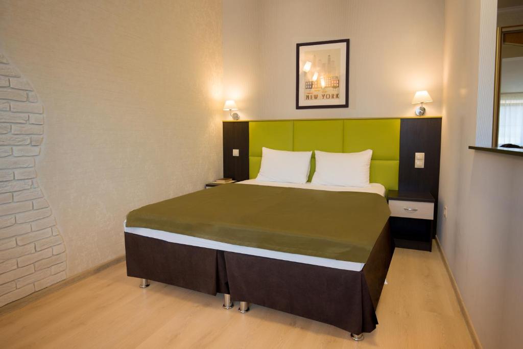 a bedroom with a large bed with a green headboard at Apart Hotel Yesenin in Kurgan