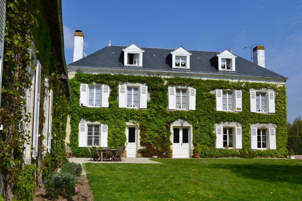 uma casa verde coberta de hera com um relvado em Le Domaine des Bois em Mauzé-Thouarsais