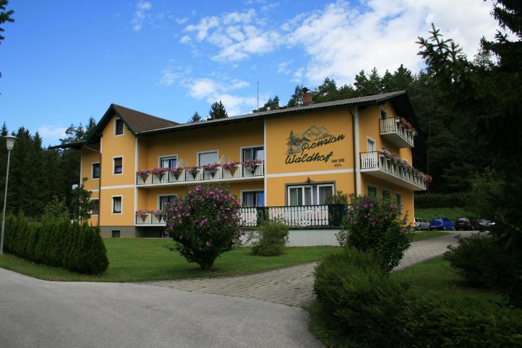 ein gelbes Gebäude mit Balkon an der Seite in der Unterkunft Appartements Waldhof in Sankt Kanzian am Klopeiner See