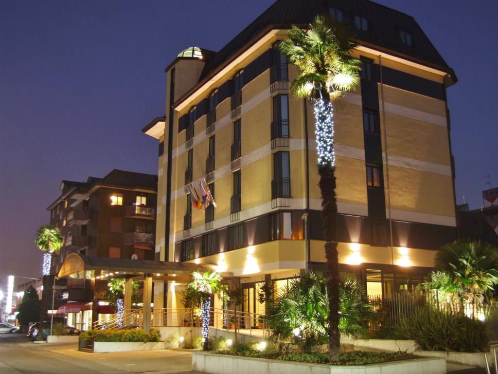 un bâtiment avec des palmiers en face de celui-ci dans l'établissement Hotel Tiffany Milano, à Trezzano sul Naviglio