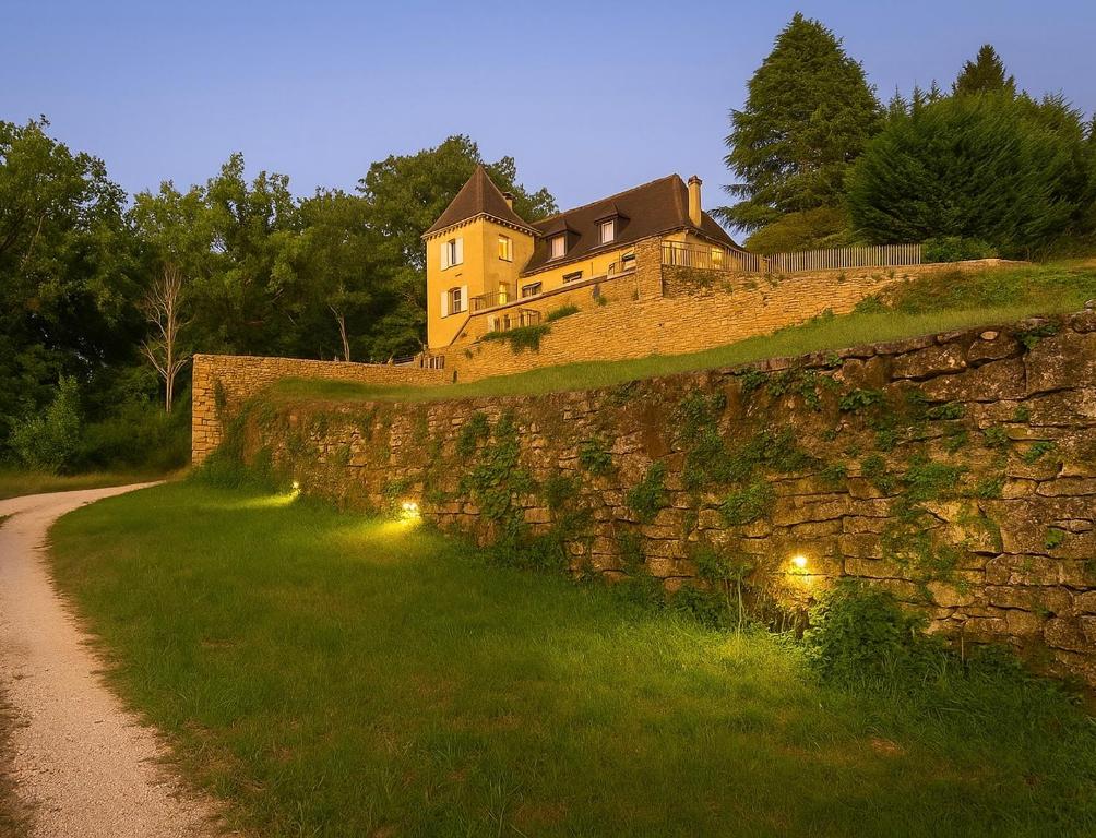 une maison sur une colline avec un mur de pierre dans l'établissement Gîte Le Vélo Rouge - Airco & Parking, à Sarlat-la-Canéda