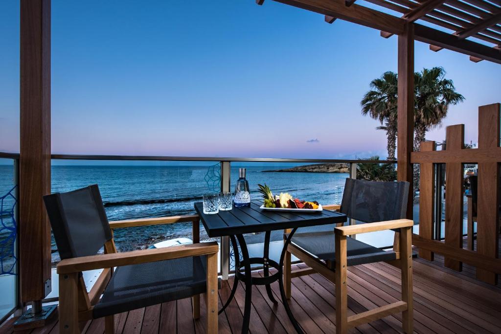 a dining table and chairs on a deck with the ocean at Infinity Blue Boutique Hotel & Spa - Adults Only in Hersonissos