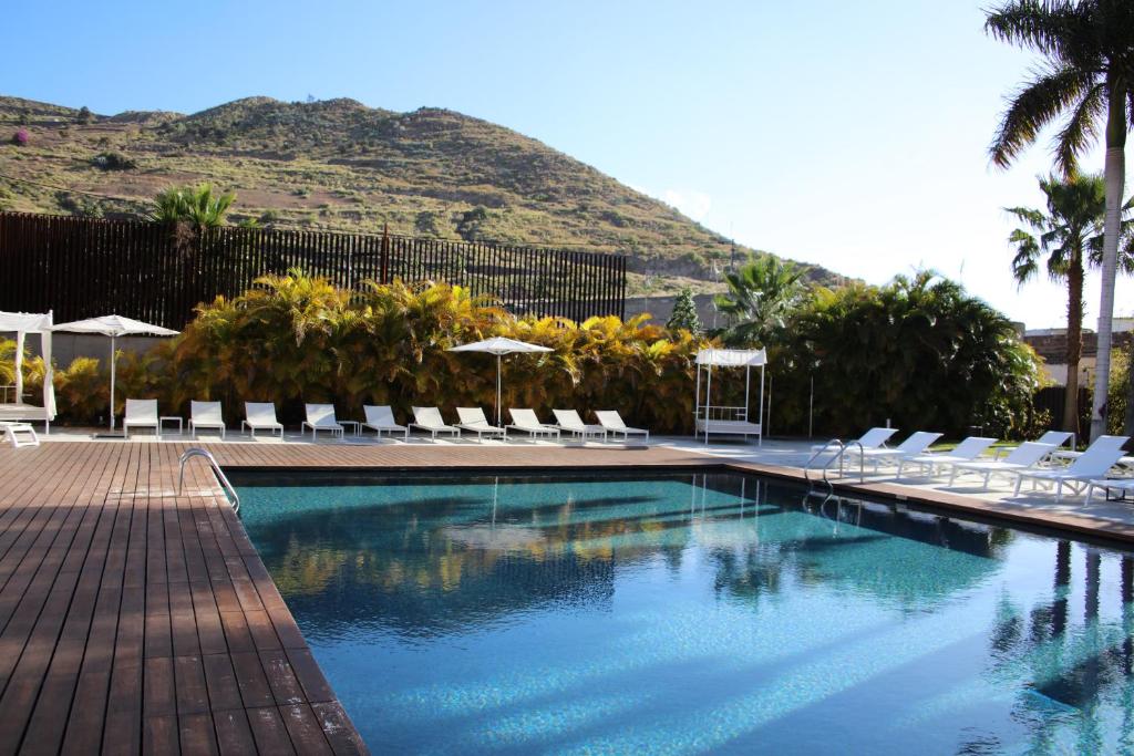 a swimming pool with chairs and umbrellas and a mountain at Iberostar Heritage Grand Mencey in Santa Cruz de Tenerife