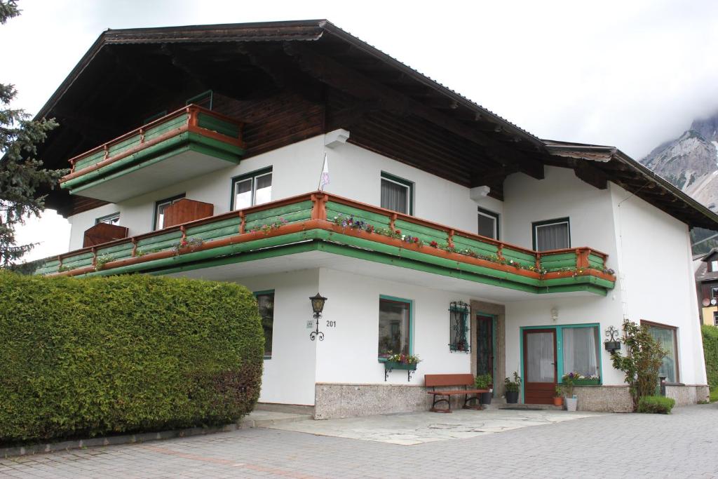 - un bâtiment blanc doté d'un balcon avec un toit dans l'établissement Haus Margit, à Ramsau am Dachstein