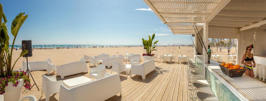 a beach restaurant with white chairs and a sandy beach at RH Bayren Hotel & Spa 4* Sup in Gandía