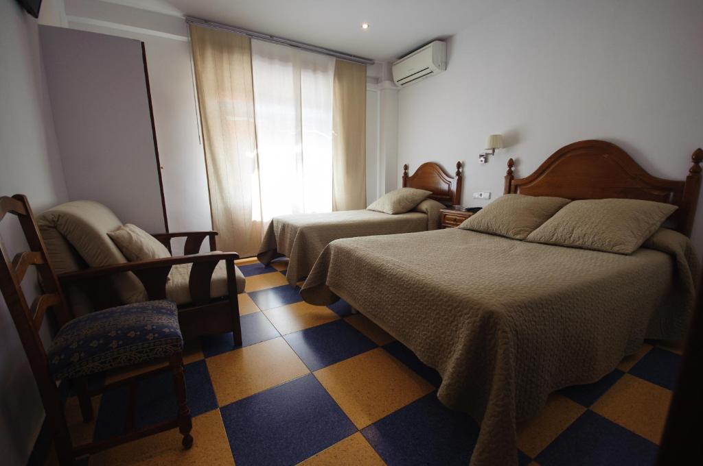 1 dormitorio con 2 camas, silla y ventana en Hostal Restaurante la Trucha, en Benavente