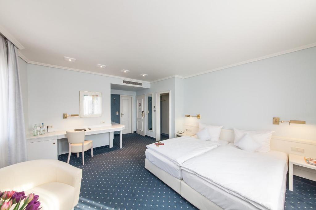 Schlafzimmer mit einem großen weißen Bett und einem Schreibtisch in der Unterkunft Novum Hotel Post Aschaffenburg in Aschaffenburg
