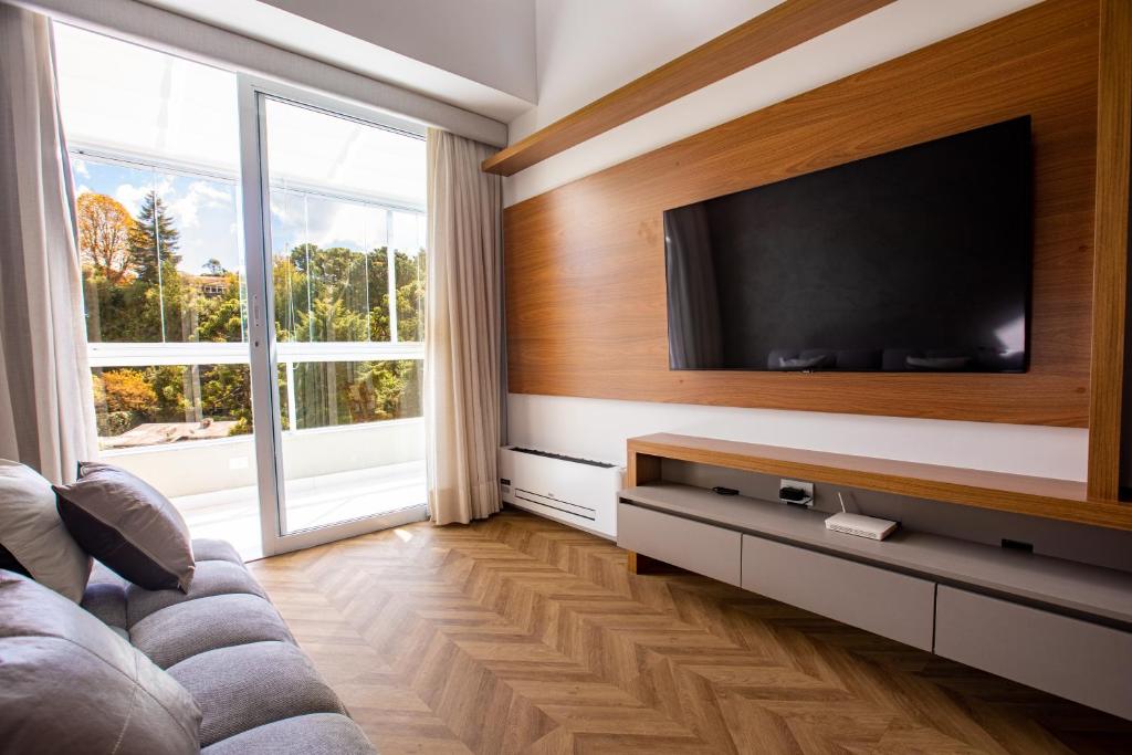 a living room with a flat screen tv on a wall at Novo Bhaus Gaudi Campos do Jordão Loft Duplex - Linda Vista - 600m do Capivari in Campos do Jordão