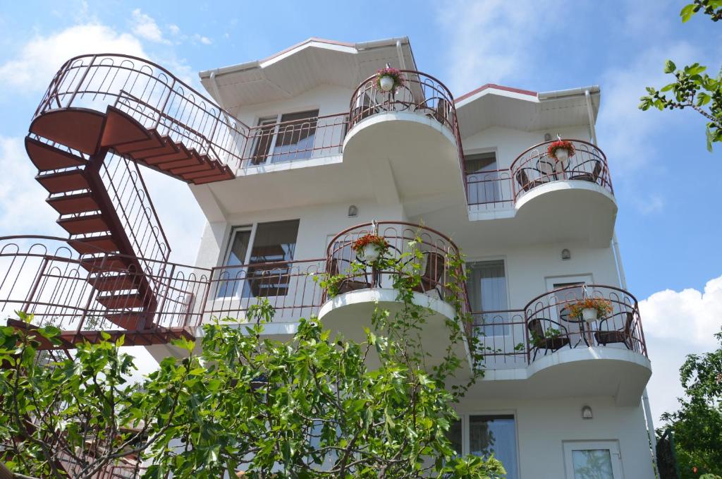 a white building with balconies and stairs at Guest House Parusnik in Alushta