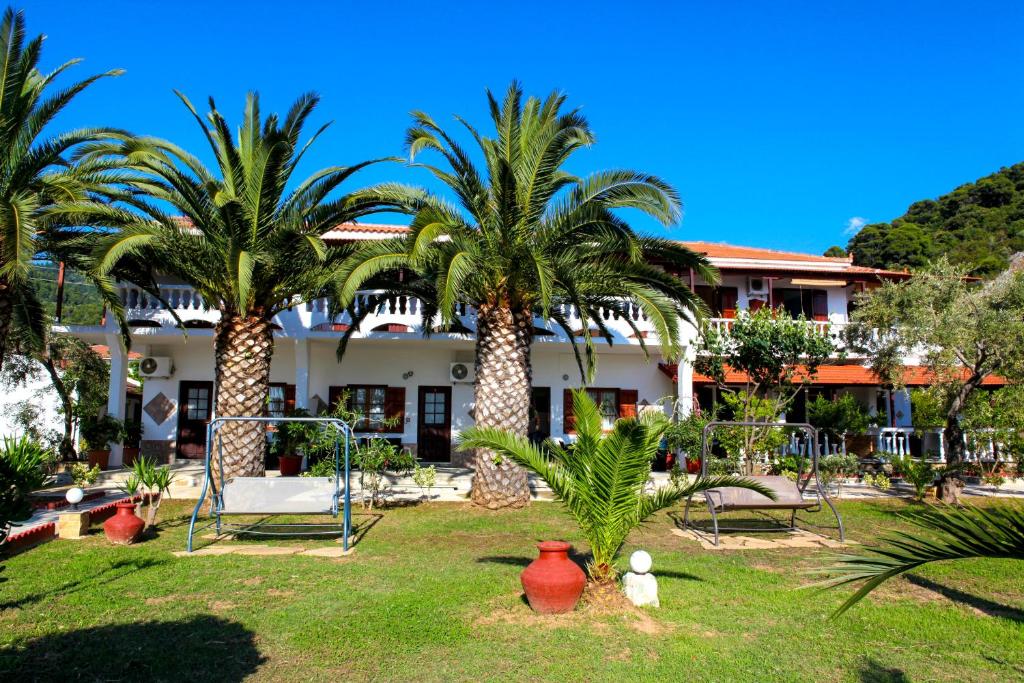 a resort with palm trees in the yard at Pelagos Beachfront in Panormos Skopelos