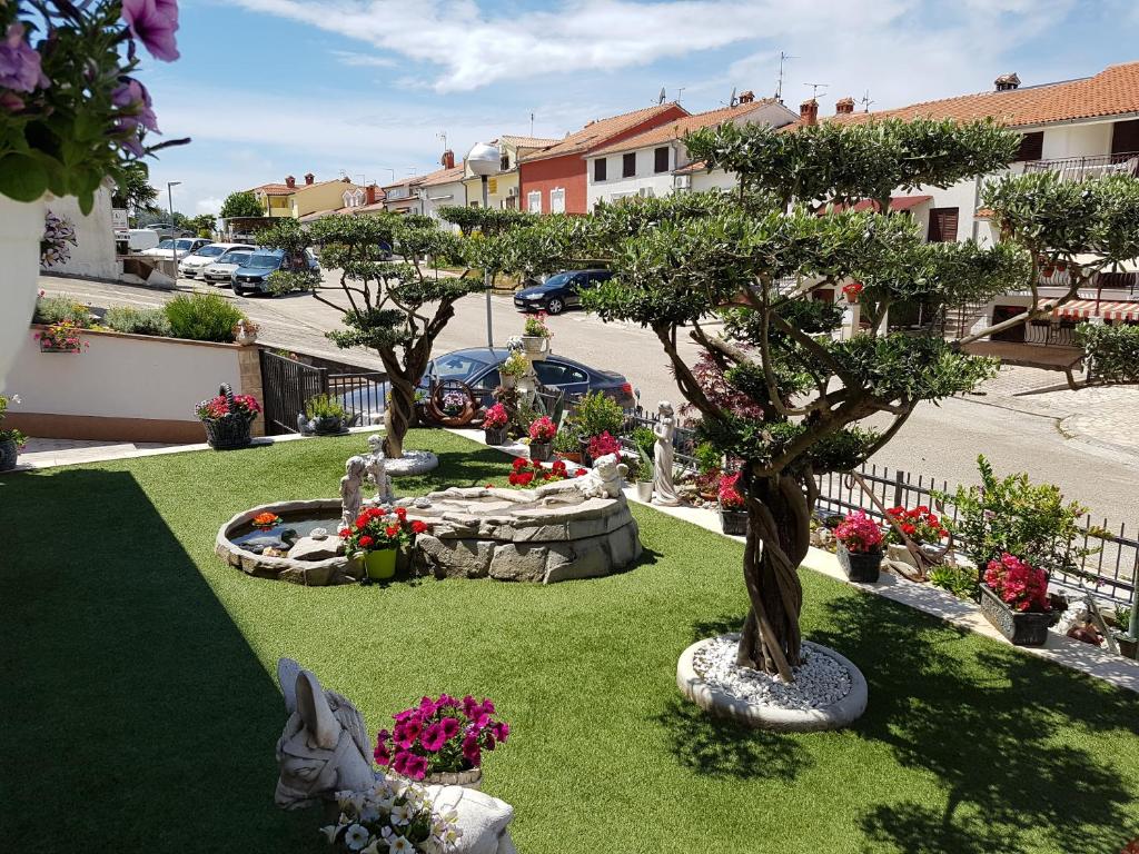 un jardin avec deux arbres et des fleurs sur l'herbe dans l'établissement Apartment Vlado, à Vrsar